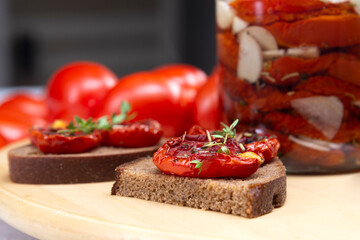 Homemade sun-dried tomatoes with olive oil in a glass jar. Sandwich with black bread and sun-dried tomatoes