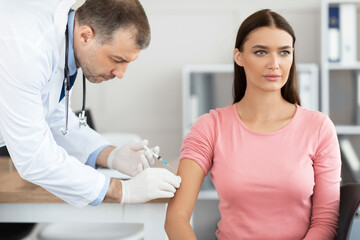 Mature doctor doing vaccination to young woman
