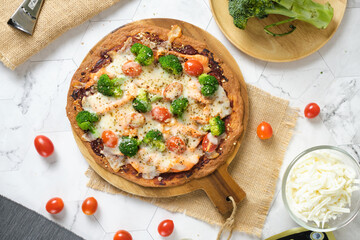 Cheesy Keto Pizza with Tomatoes Broccoli And Salmon for ketogenic diet. set on white cafe table.