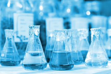 Chemical beaker in laboratory with atomic chart