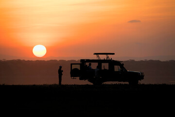 Fototapeta premium African safari car in red dawn sunrise with unknown silhouettes