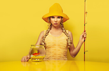 Portrait of a young fisherwoman looking at the camera, dressed in a yellow dress with a fish...