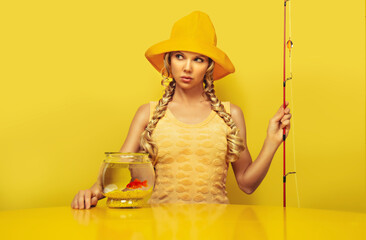 Portrait of a young fisherwoman  patiently waiting, dressed in a yellow dress with a fish pattern,...