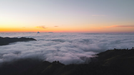 Obraz premium View of a sunrise from a mountain surrounded by clouds