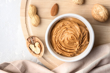 Obraz na płótnie Canvas Walnut butter made of peanuts, almonds and walnut on a grey background.