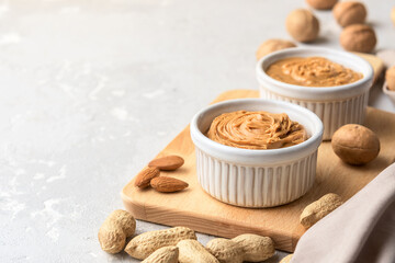Fototapeta na wymiar Walnut butter made of peanuts, almonds and walnut on a grey background.