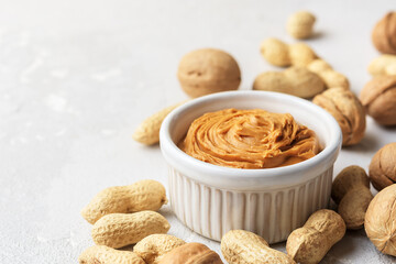 Walnut butter made of peanuts, almonds and walnut on a grey background.