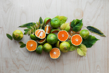 Lots of tangerines and autumn leaves on a light table. Background image. Place for text. Flat lay.