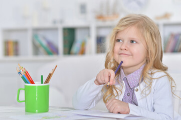 Portrait of cute smiling girl drawing at home