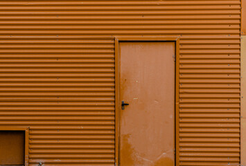 Fachada de metal corrugado con puerta de color naranja