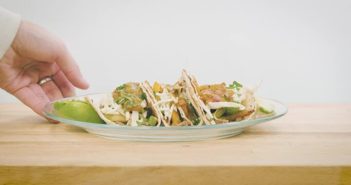 Man Setting Down A Plate Of Tacos On A Wood Countertop.  Three Vegetarian Tacos Made With Calabacitas And Smothered In Fresh Salsa On A Taqueria Counter.