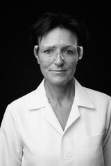 Mature beautiful woman doctor with short hair against black background