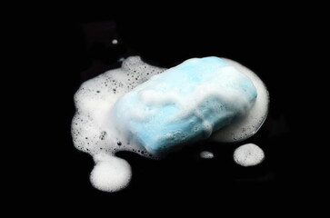 Soap bar with foam isolated on black background. Wet bar of soap.