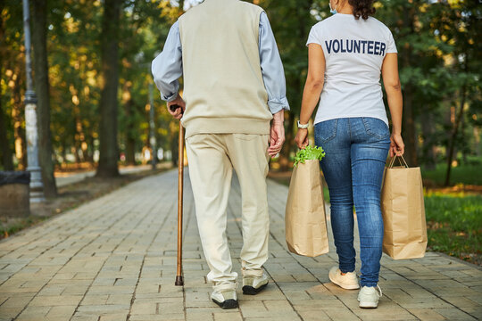 Female helping with paper shopping bags to the old man