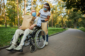 Female volunteer helping to the mature disabled man