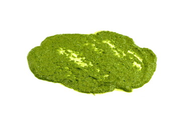 Pesto spread or blob in a bowl isolated on white background. Green italian homemade spilled sauce made of ground basil, garlic, pine seeds, olives and pecorino sardo cheese 