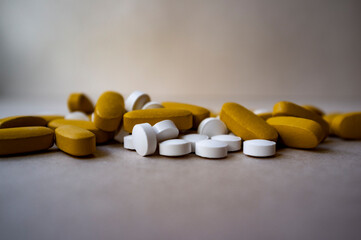Multi tablets, white and fawn medicine pills on grey and brown background, vitamin pills, nutrition...