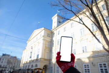 woman hand in red gloves holding phone with white screen lviv city hall on background