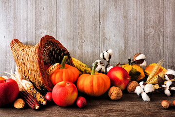Thanksgiving harvest cornucopia filled with autumn fruits and vegetables. Side view against a...