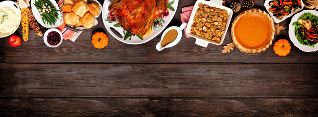 Traditional Thanksgiving turkey dinner. Above view top border on a dark wood banner background with copy space. Turkey, mashed potatoes, dressing, pumpkin pie and sides. - obrazy, fototapety, plakaty