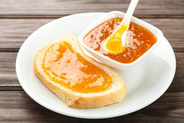 Fototapeta na wymiar Toast with apricot jam in bowl on wooden table