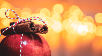 roter Apfel mit Zimtstangen vor Lichter Bokeh Hintergrund zu Weihnachten. red apple with cinnamon...