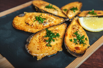 Shellfish mussels with herbs and lemon on the cutting board.