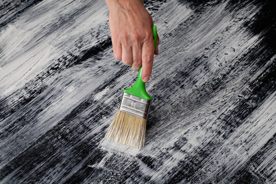 Home renovation, plank floor painting to white and black, shabby chic combination with workers hand and brush