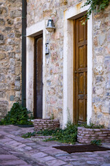 Plakat Wooden door in the stone wall of the building. Ivy plant by the door
