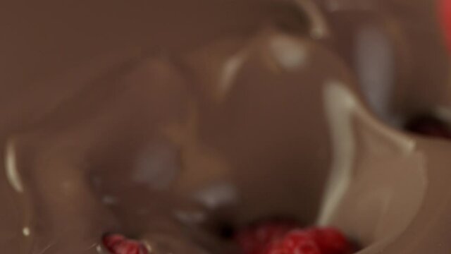 Super slow motion of pouring dark hot chocolate with raspberries. Filmed with cinema high speed camera, 1000fps.