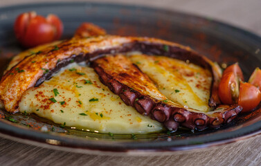 pulpo a la gallega sobre pure de patatas y tomates cherry