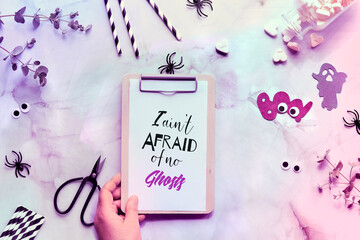 Clipboard with text I ain't afraid of no ghosts on neon toned Halloween stone background with decor