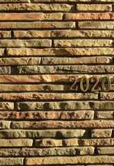 Autumn or fall of 2020. Inscription in golden numbers 2020 on the stone (docorative bricks) wall, symbolizing going out autumn. Autumn season concept, holidays and celebration Postcart or mock-up