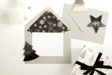 Christmas background with envelopes, invitation card, gift box, decorations in gray black colors on white  background. Top view. copy space