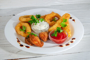 Deep-fried breaded onion rings on a plate with herbs