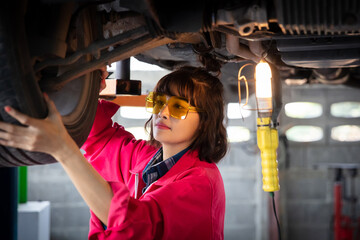 Young Female technician using lighting check underbody of car - obrazy, fototapety, plakaty