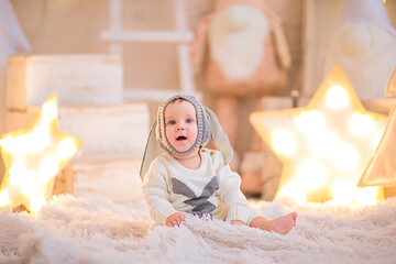 Fototapeta premium Baby boy in Christmas suit like a rabbit posing in a room with Christmas decor.