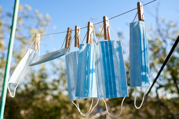 Sunlit face masks are hung to dry for disinfection fastened by wooden clothespins. New normal...