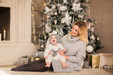 Mother posing with her baby boy in Christmas suit on Christmas background.