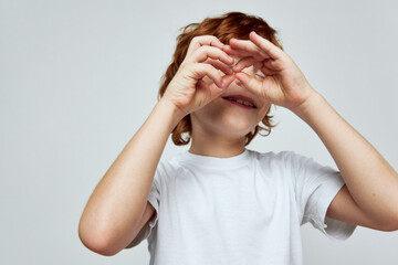 Portrait of red-haired boy hands near face emotion smile white t-shirt