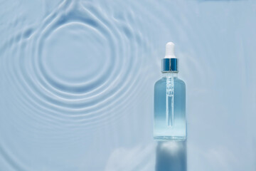 Cosmetic spa medical skin care, bottle for serum, micellar toner and emulsion on water texture background with splashes. Flat lay, copy space.