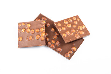 Pieces of milk chocolate with whole hazelnuts on white background