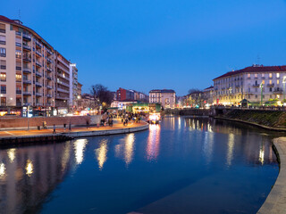 Fototapeta na wymiar Beautiful view of Darsena in the touristic district of Milan during the blue hour and the lights of the city can be seen reflected on the water.Lombardy, Italy