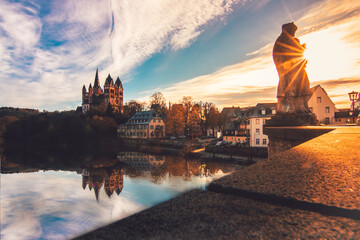 The cathedral in Limburg Germany.  nice view over an old bridge with statue and the river at sunrise - obrazy, fototapety, plakaty