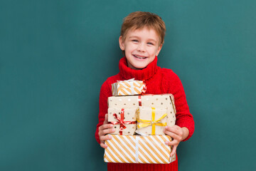 Kid boy in a red sweater with Christmas gift boxes. Christmas shopping. birthday. Copy space. new normal.