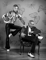 Vintage black and white portrait of a couple from the 70s, posing in front of a butterfly pattern...