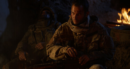 Fototapeta premium Soldier resting near fire at night