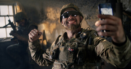 Fototapeta premium Military man using smartphone inside grungy building