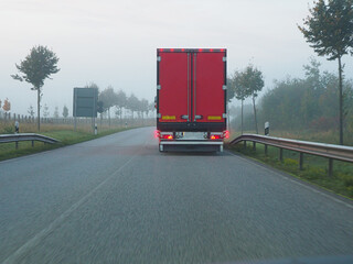  red truck driving on a foggy country road