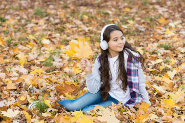 Lost in thoughts. fall maple leaves in park. online education. childhood happiness. beauty and nature. happy kid wear headphones. girl listen music on the way to school. child relax in autumn forest